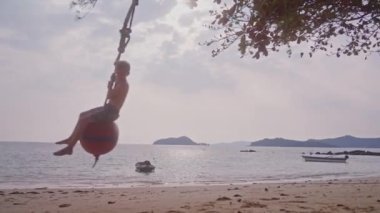Tayland 'da gündüz vakti iki farklı şamandıra üzerinde salıncak süren bir kızla bir oğlanı gösteren bir video.