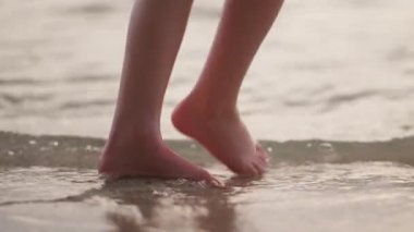 Gündüz vakti deniz suyunda yürürken görülebilen bir çift ayağın yakın çekim görüntüsü.