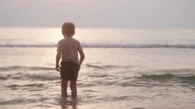 Tayland 'da gün batımında deniz suyunda birkaç kez zıplayan bir çocuğun videosu.