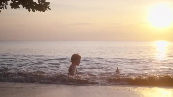 在泰国 男孩在日落时分坐在海边平静的水面上 — 图库视频影像