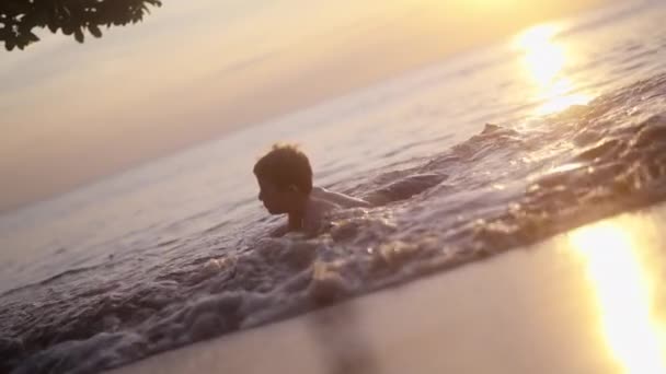 Video Chlapce Ležícího Pláži Malými Vlnami Narážejícími Pobřeží Při Západu — Stock video