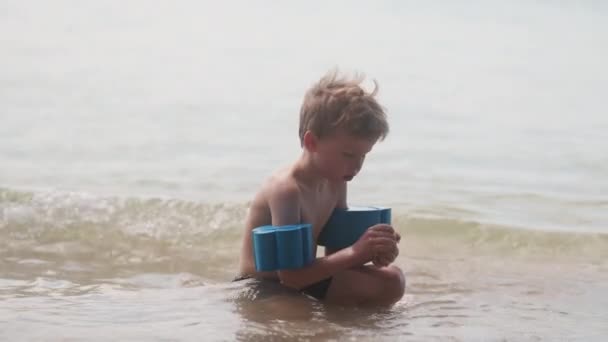 Ung Pojke Med Armflottörer Som Hukar Sig Strandvatten Nära Stranden — Stockvideo