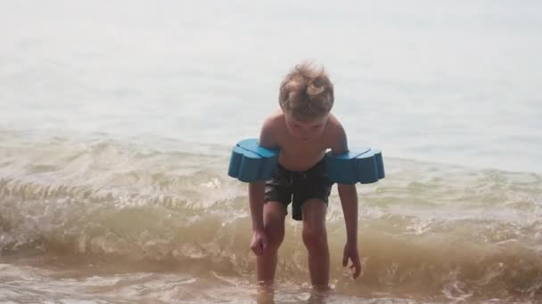 Ein Kleiner Junge Mit Armschwimmern Steht Tagsüber Thailand Strandwasser Ufernähe — Stockvideo