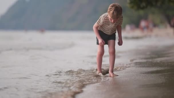 昼間に砂が手を振って海岸線に沿って少年のビデオ — ストック動画