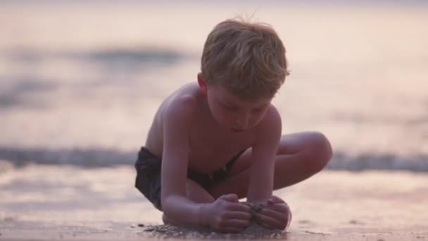 在泰国 一个男孩日落时在海滩上吹制沙子的视频 — 图库视频影像