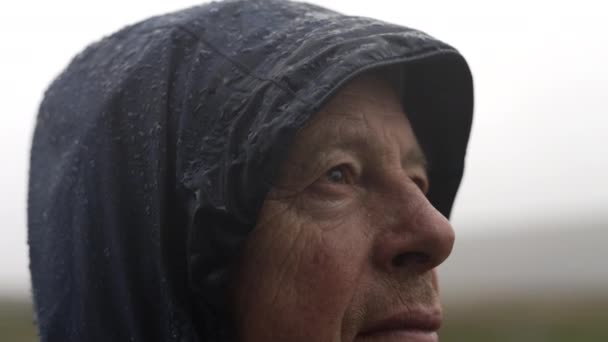 一位穿着雨衣的中年男子站在冰岛乡间的雨中进行特写 — 图库视频影像