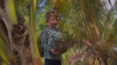 Rashguard takan genç bir çocuk Tayland 'da gündüz vakti yere olgun bir hindistan cevizi fırlatıyor.