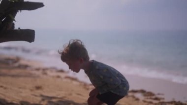 Tayland 'da gündüz vakti kumsalda kumla oynayan bir çocuğun videosu.