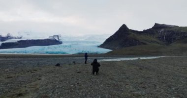 İki adamın fotoğraf çekerken ve İzlanda 'nın donmuş buzul vadisinde insansız hava aracı kullanırken geniş açılı görüntüler.