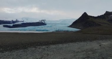 İzlanda 'daki bir vadide mavi buzul oluşumlarına yaklaşan bir insansız hava aracının POV görüntüsü.