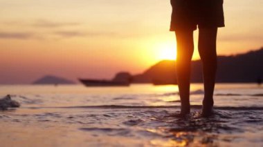 Gün batımında Tayland 'da bir sahilde denize atlayan birinin videosu.