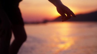 Gün batımında Tayland 'da bir plajı işaret eden bir çocuğun kolunun videosu.