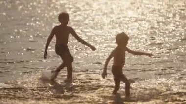 Tayland 'da gün batımında çocuklar sahilde su tekmeliyor.