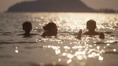 Gün batımında Tayland 'da bir sahilde oynayan çocukların videosu.