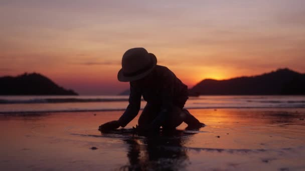 一个视频中 一个小男孩跪在海滨玩湿沙子 日落时用手在泰国海滩上玩 — 图库视频影像