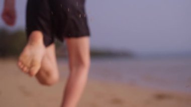 Tayland 'da bir sahil boyunca ağır çekimde koşan küçük bir çocuğun gündüz görüntüsü.