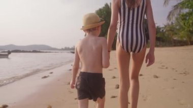 Tayland 'da bir sahilde yürüyen bir kızla bir oğlanın videosu.