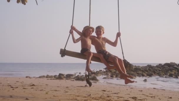 在一个阳光灿烂的日子里 两个男孩在泰国海滩荡秋千的视频 — 图库视频影像