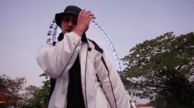 Bir break dansçı dans ederken şapkasının kenarına dokunur ve yavaşça kameraya bakar.