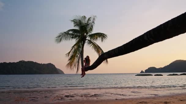タイのビーチでヤシの木の幹に座っている3人の子供のビデオ — ストック動画