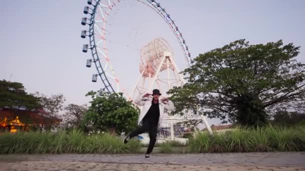 Танцовщица Стильной Куртке Танцует Замедленной Съемке Перед Колесом Обозрения Парке — стоковое видео