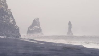 Kuvvetli rüzgarlar ve akın eden deniz dalgaları, Reynisdrangar bazalt kaya oluşumlarına fırtına sırasında İzlanda 'daki Reynisfjara plajı yakınlarında çarpar.