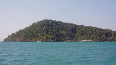 Tayland 'da gündüz vakti mavi okyanusta uzaklardan yeşil bir tropikal adanın videosu.