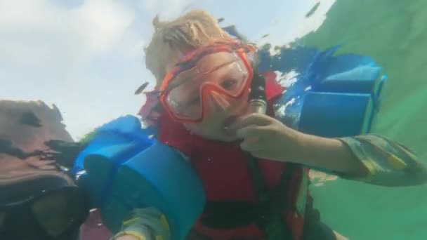 タイの昼間にカメラを指しているシュノーケリング用具を身に着けている小さな男の子の水中ショット — ストック動画