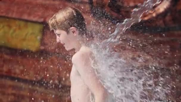 タイのウォーターパークで背中に水を浴びている男の子のビデオ — ストック動画