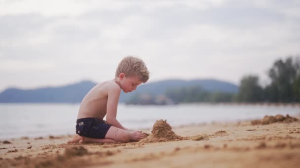 Ένα Βίντεο Ένα Νεαρό Αγόρι Μαζεύει Άμμο Μια Παραλία Στην — Αρχείο Βίντεο