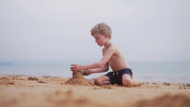 砂を積み上げ タイのビーチに砂の城を構築しようとしている少年のビデオ — ストック動画