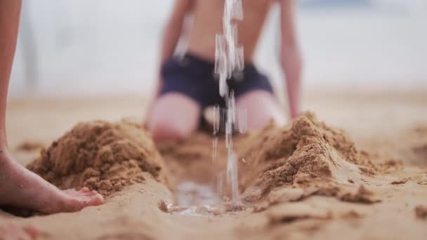 一段录像显示 当小男孩在泰国的一个海滩上观看时 沙子上的水正在倾泻下来 — 图库视频影像