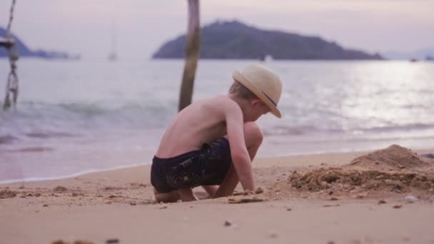 タイの昼間に砂の掘削をしている海岸の少年のビデオ — ストック動画