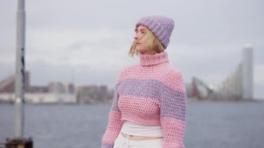 Pembe ve mor yün kazak giyen bir kadının güzelliğini gösteren bir kavisli fotoğraf.