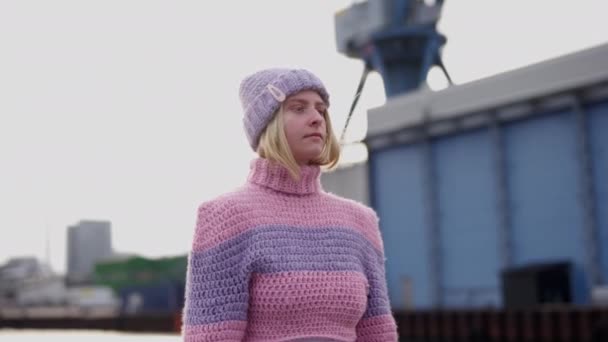一个女人静静地站在视频的中心 穿着一件粉色和紫色羊毛衫 — 图库视频影像