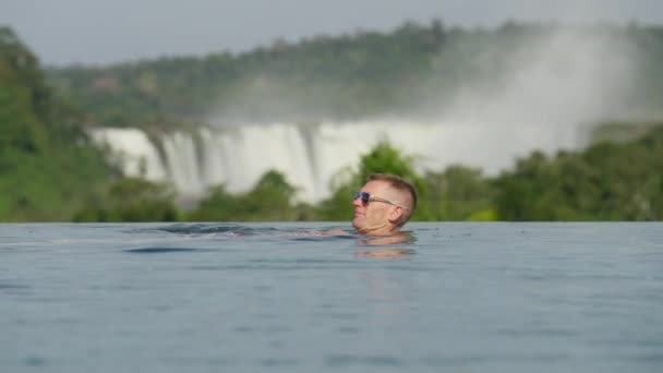 Een Man Met Een Zonnebril Drijft Zwemt Een Zwembad Buurt — Stockvideo
