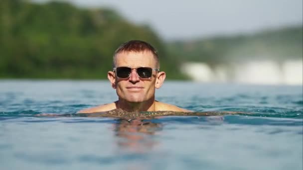 Detailní Záběr Muže Tmavými Slunečními Brýlemi Plavajícího Bazénu Poblíž Vodopádů — Stock video