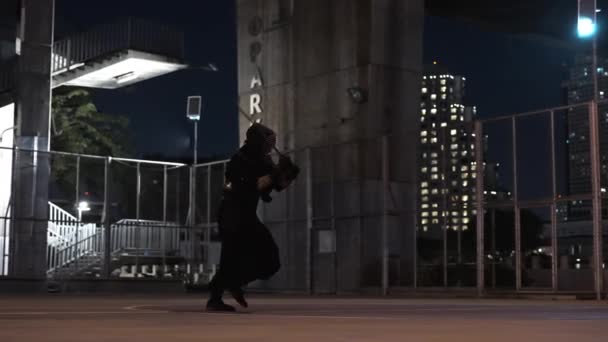 男は都市都市で夜間に剣道の練習でスムーズにバックステップを実行する — ストック動画