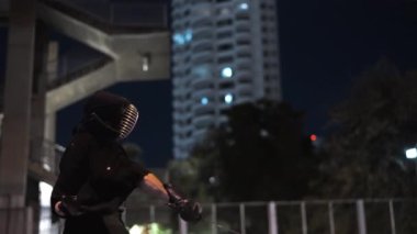 Kendo pratisyeninin gece çekilen yan görüntüsü, grevlerin ritmik değişimiyle meşgul oluyor.