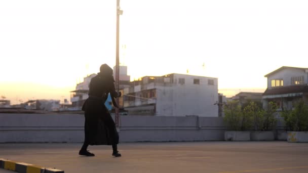 伝統的な剣道の衣装の男は 夕日中に屋上でひざまずいたスタンスを実行します — ストック動画