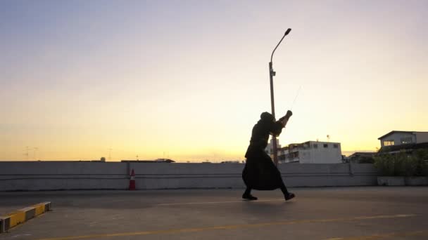 剣道を身に着けている男が 夕日には屋上で剣技を練習する — ストック動画