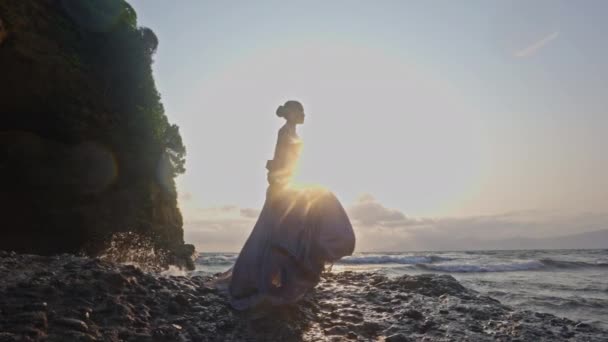 Eine Frau Spitzenkleid Steht Vor Dem Orangefarbenen Sonnenuntergang Felsigen Meeresufer — Stockvideo