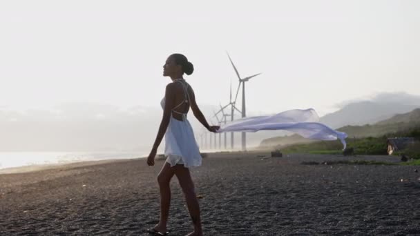 Kobieta Białej Sukience Trzymająca Szalik Prawej Ręce Szczęśliwie Spacerująca Wybrzeżu — Wideo stockowe
