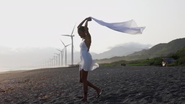 Kobieta Białej Sukience Trzymająca Szalik Nad Głową Szczęśliwie Spacerująca Brzegu — Wideo stockowe