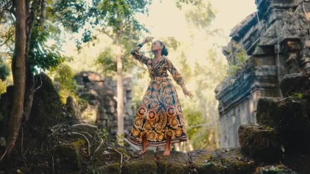 Kobieta Eleganckiej Sukience Złotych Akcesoriach Pozuje Świątyni Pokrytej Mchem Kambodży — Wideo stockowe