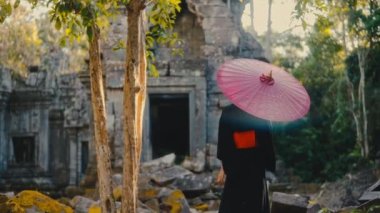 Siyah kimonolu, kırmızı şemsiyeli, yosun kaplı tapınağın etrafında dolaşan bir kadının arka plan fotoğrafı.