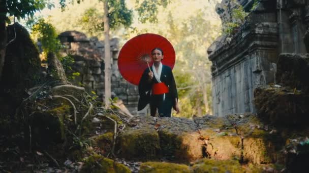 Woman Draped Black Kimono Carries Red Umbrella While Wandering Abandoned — Stock Video