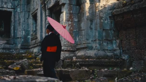 Zdjęcie Tyłu Kobiety Czarnym Kimono Trzymającej Czerwony Parasol Przechodzącej Obok — Wideo stockowe