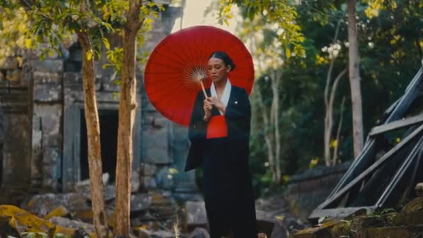 Eine Schwarzen Kimono Gekleidete Frau Mit Einem Roten Papierschirm Erkundet — Stockvideo