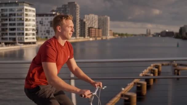 Hombre Mirando Río Mientras Monta Bicicleta — Vídeo de stock